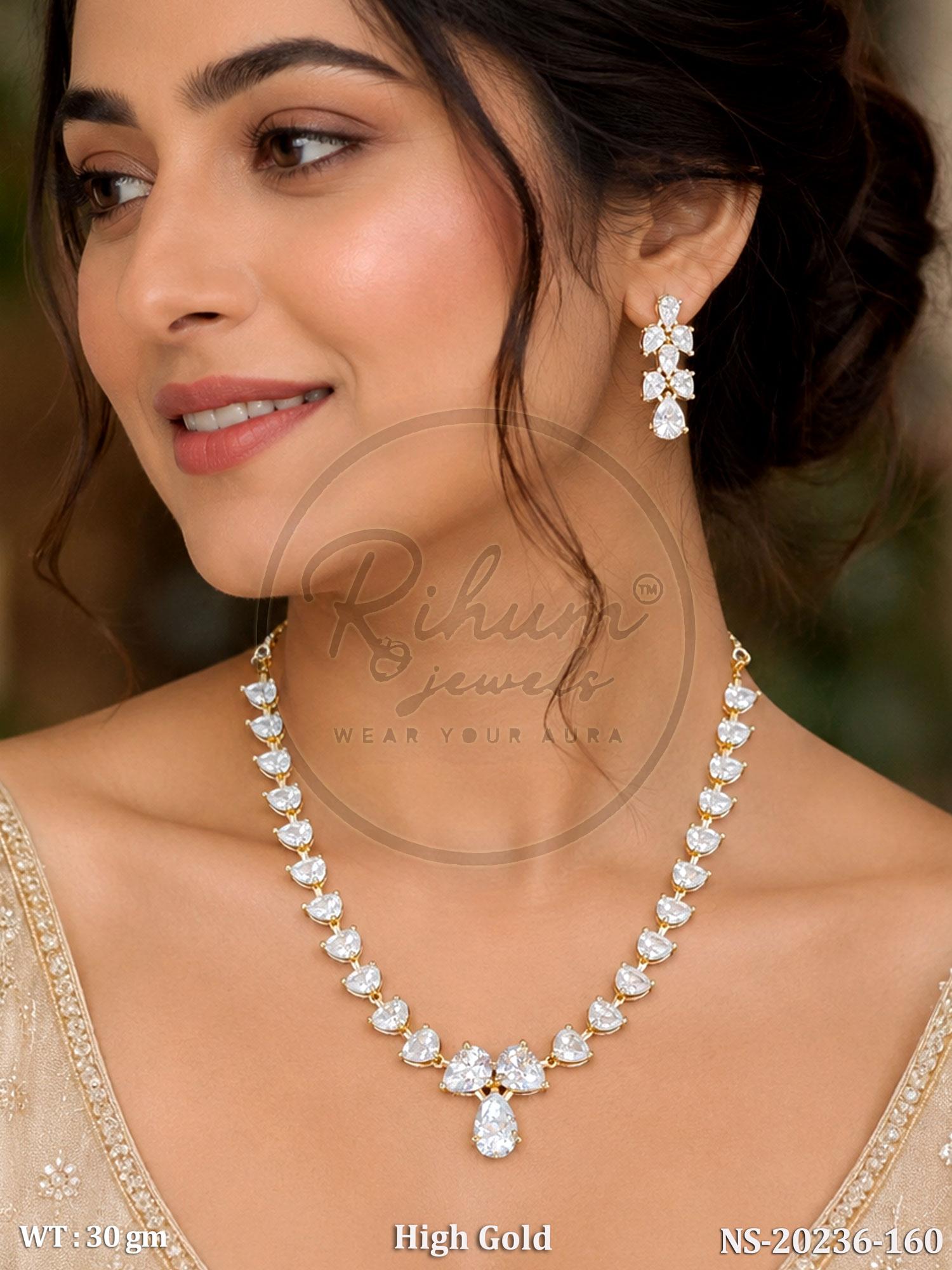 A close-up of a woman wearing a high-gold necklace and matching drop earring with clear stones. The jewelry is shown on a model, with a watermark reading 'Rihuz jewelry' across the center.