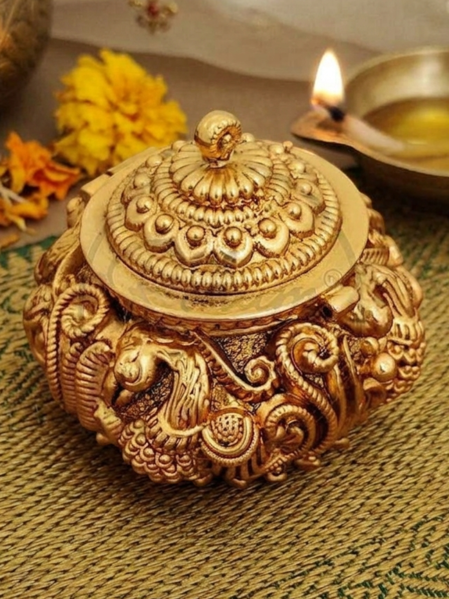 Rihum Jewels gold-plated antique kumkum box with intricate peacock Nakshi engravings and a hinged lid for puja rituals.