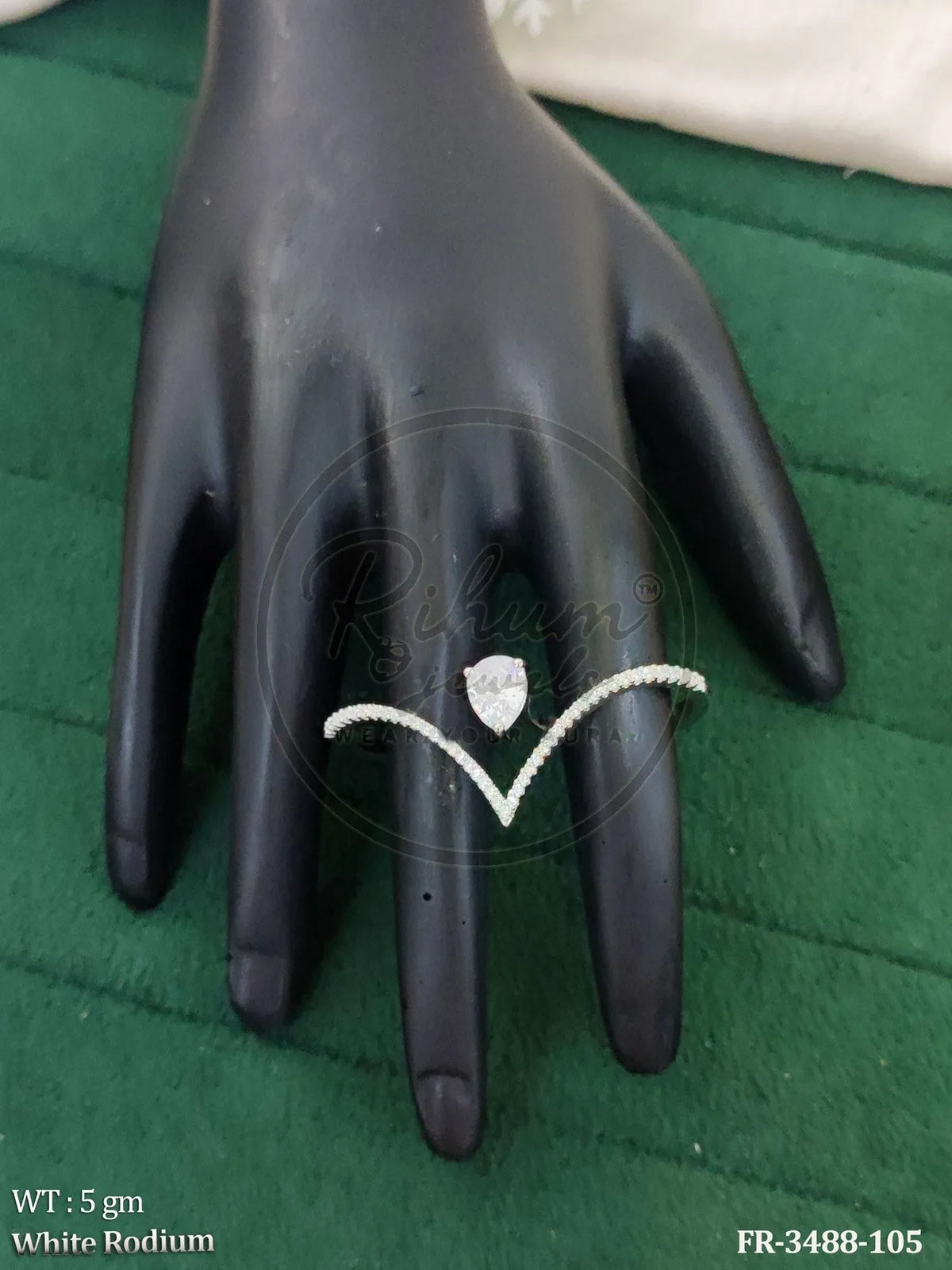 Rihum Jewels V-shaped statement ring with a pear-cut stone and shimmering accents on a rhodium-plated band.